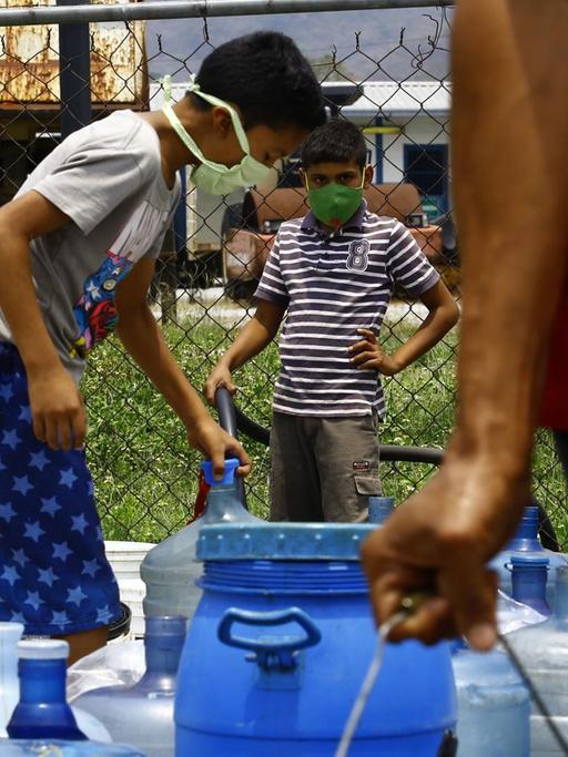 Menschen füllen Wasserkanister in Naguanagua, Venezuela.