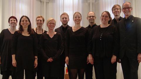 Gruppenbild des Chores.mit neun Sängerinnen und Sängern und der Chorleiterin.