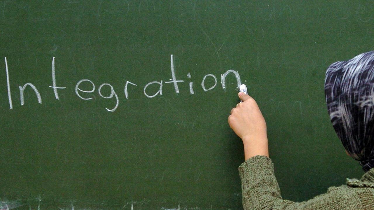 Eine türkische Frau schreibt im Schulungsraum der interkulturellen Frauenbegenungsstätte "verikom" in Hamburg-Wilhelmsburg das Wort "Integration" an die Tafel. Eine türkische Frau schreibt im Schulungsraum der interkulturellen Frauenbegenungsstätte "verikom" in Hamburg-Wilhelmsburg das Wort "Integration" an die Tafel.