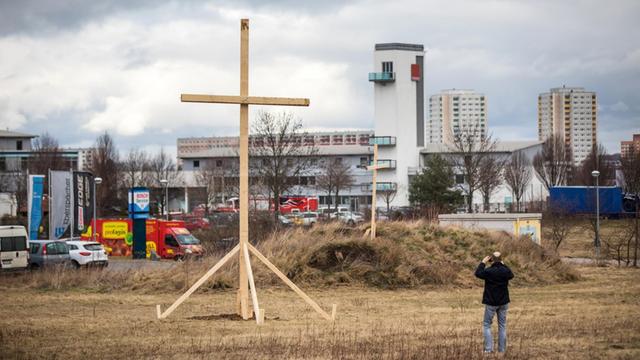 Eine Mann fotografiert in Erfurt ein großes Holzkreuz auf einem Grundstück in der Nähe der als Baugrund für den Moschee-Neubau vorgesehenen Fläche.