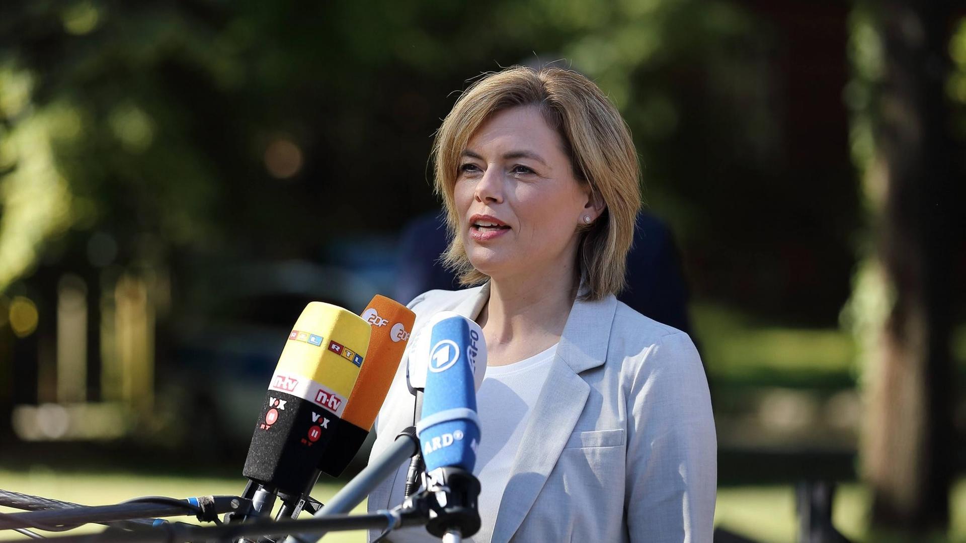 Julia Klöckner spricht vor Bäumen in Mikrofone Julia Klöckner spricht vor Bäumen in Mikrofone
