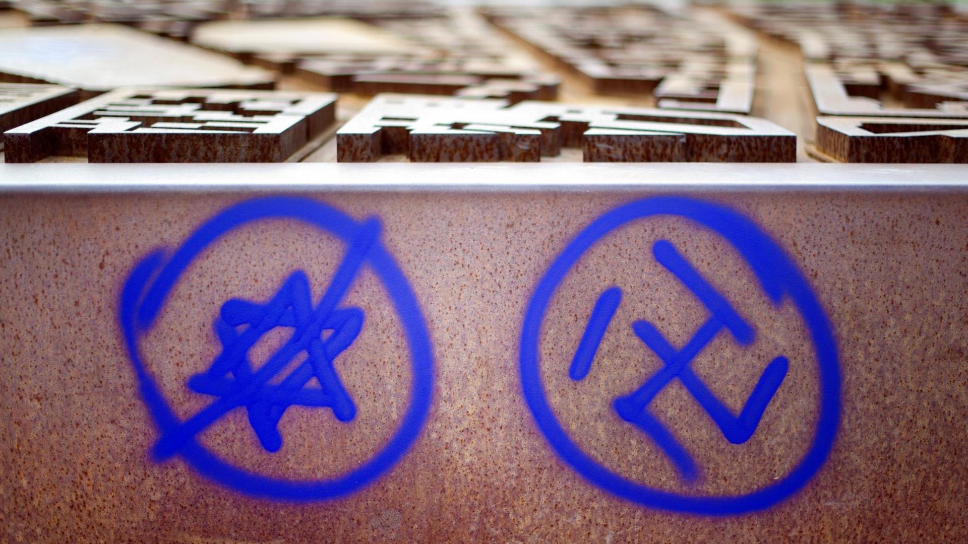 Ein Hakenkreuz und ein durchgestrichener Davidstern sind an einer Gedenkstätte zu sehen. Ein Hakenkreuz und ein durchgestrichener Davidstern sind an einer Gedenkstätte zu sehen.