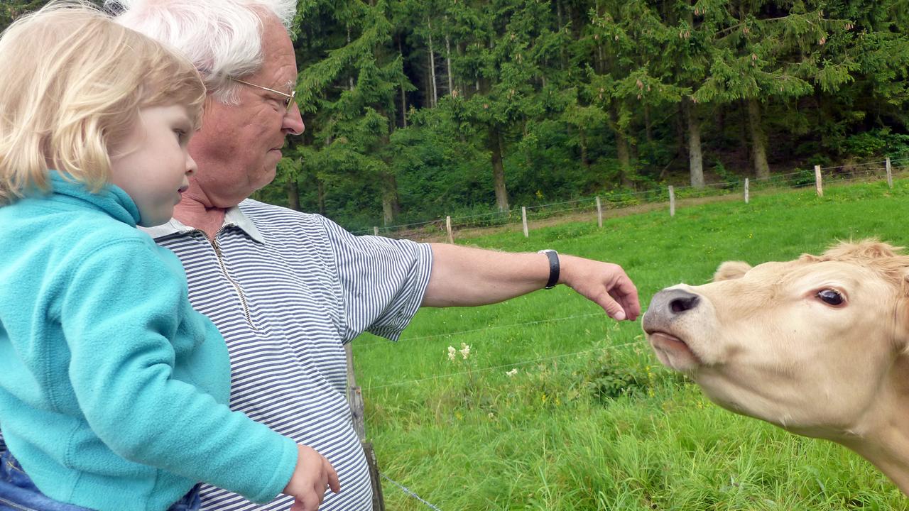 Günter, der Vater des Autors Thilo Schmidt, mit seiner Enkelin Pauline auf dem Arm, er streichelt eine Kuh Günter, der Vater des Autors Thilo Schmidt, mit seiner Enkelin Pauline auf dem Arm, er streichelt eine Kuh