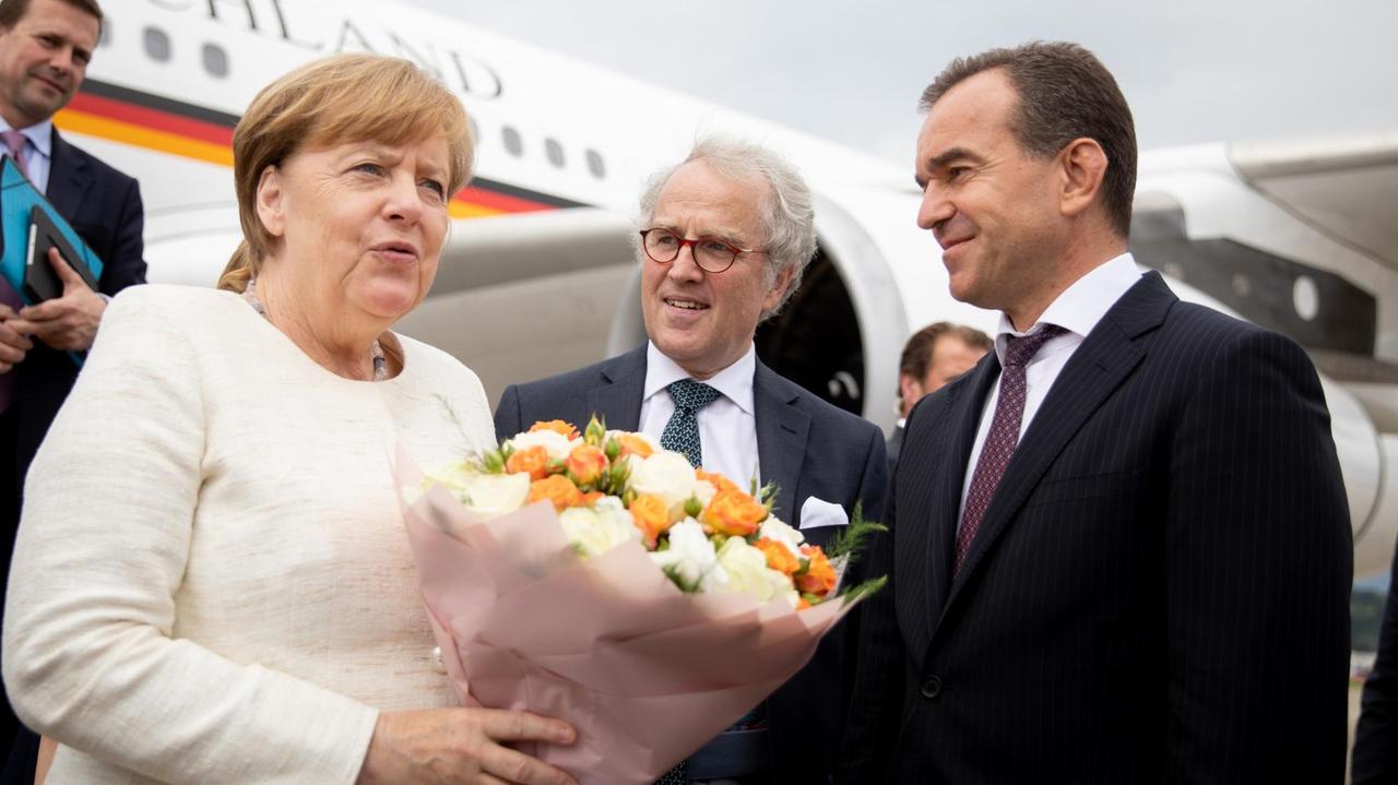 Bundeskanzlerin Angela Merkel (CDU) wird von dem Gouverneur der Region Krasnodar, Weniamin Iwanowitz Kodratjew (r) und dem deutschen Botschafter in Russland Rüdiger Freiherr von Fritsch (M), nach ihrer Ankunft am Internationalen Flughafen Sotschi begrüßt.