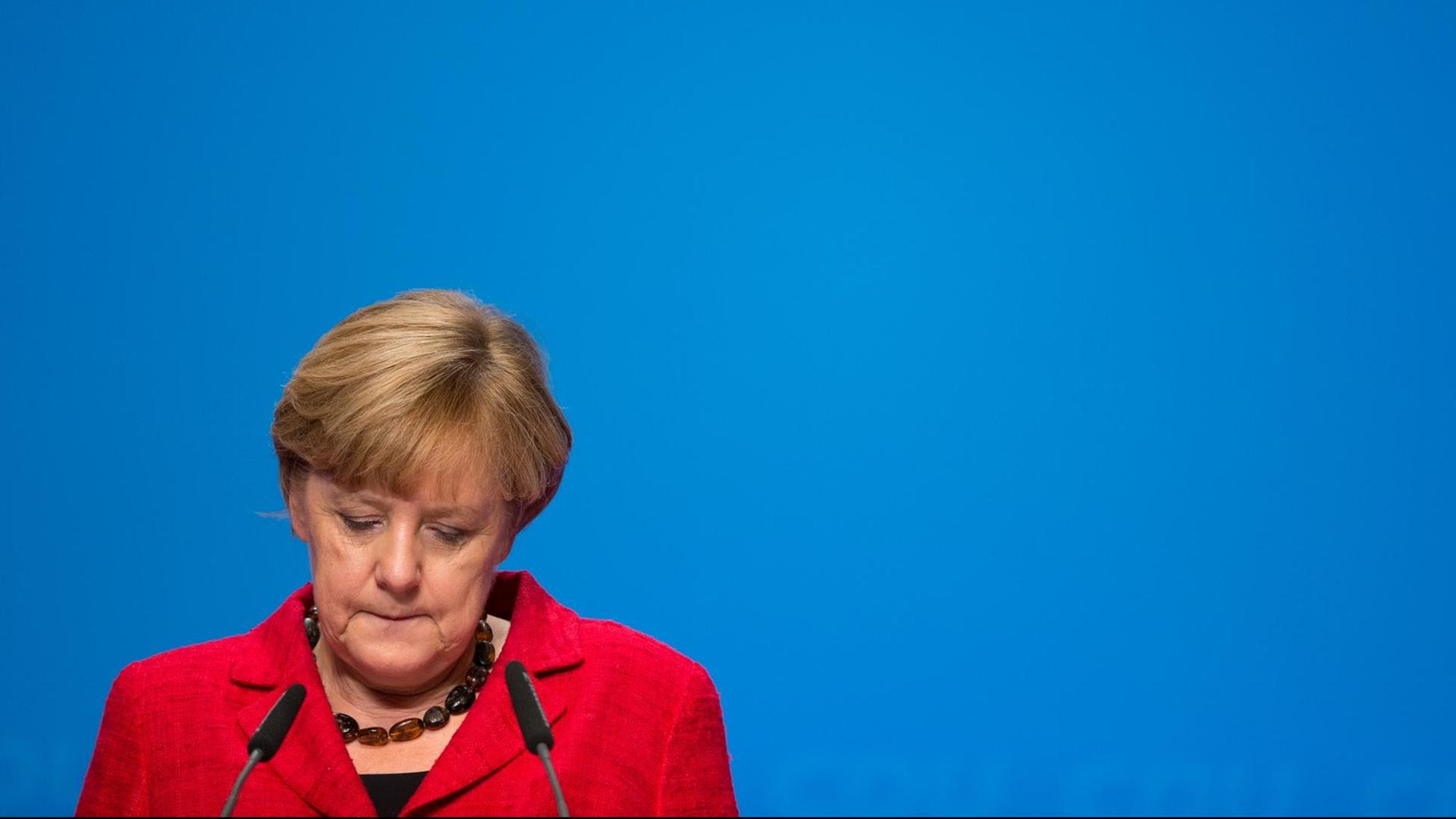Bundeskanzlerin Angela Merkel vor einem Rednerpult; sie blickt nach unten. Bundeskanzlerin Angela Merkel vor einem Rednerpult; sie blickt nach unten.