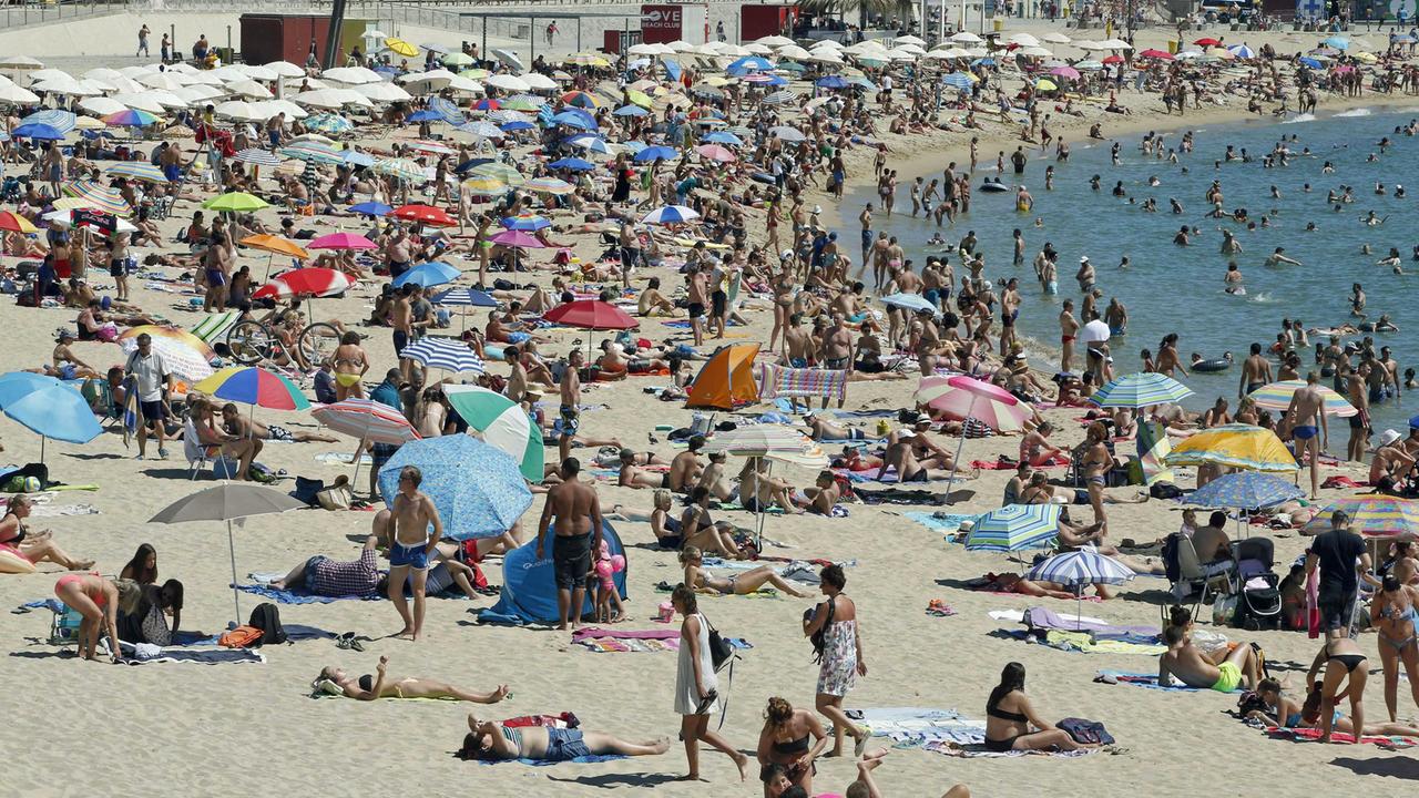 Tausende Touristen genießen die Sonne am Strand von Barcelona.