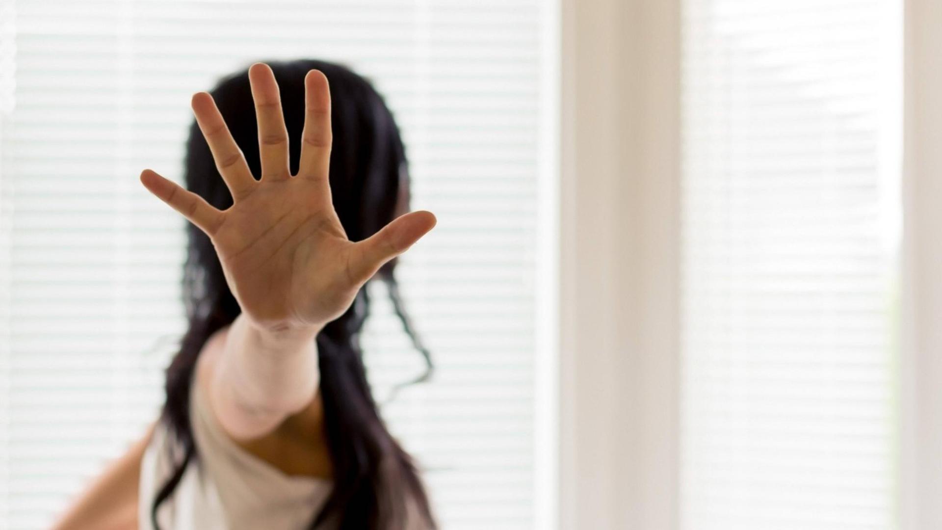 Eine Frau wird belästigt und hält die Hand zur Abwehr Eine Frau wird belästigt und hält die Hand zur Abwehr