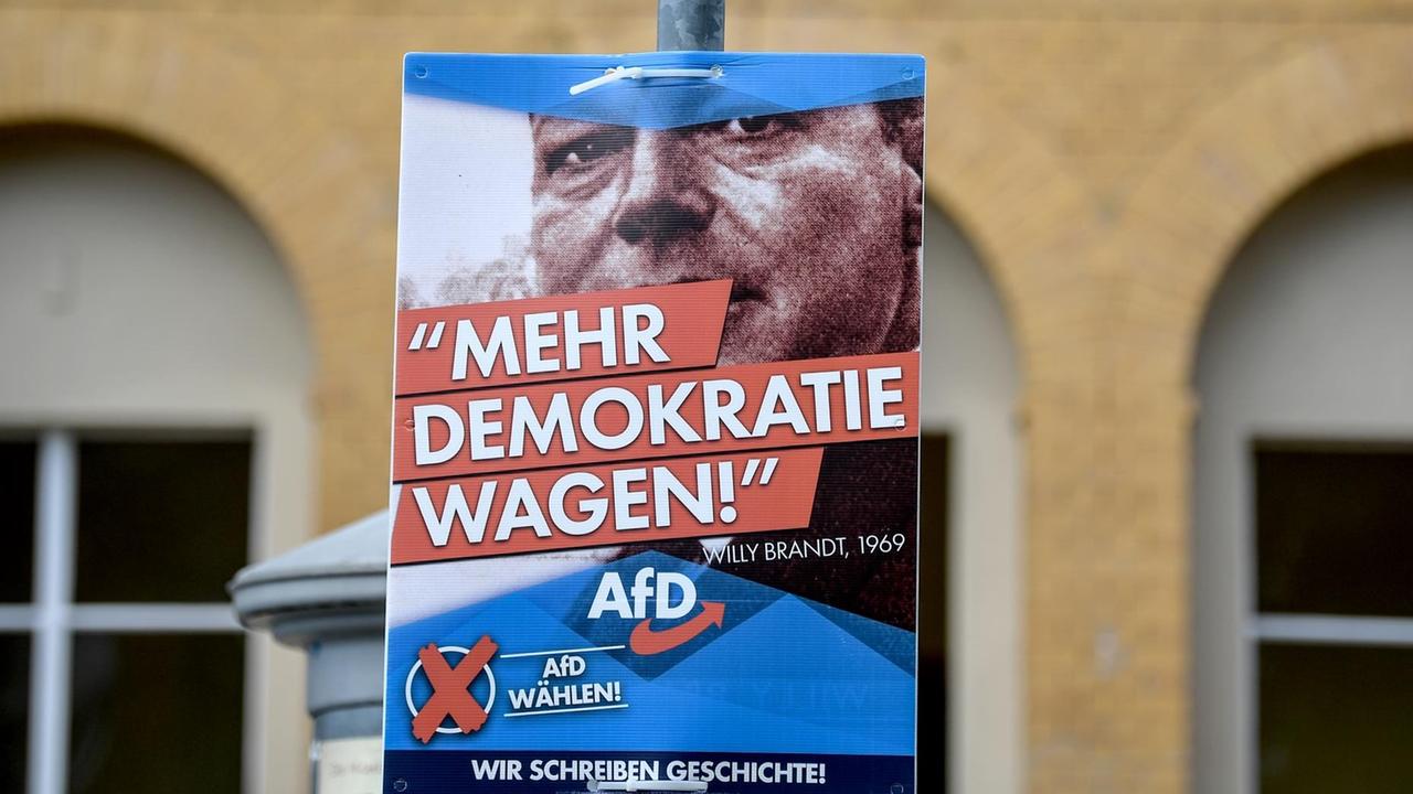 ARCHIV - 08.08.2019, Brandenburg, Michendorf: Ein Plakat mit einem Bild des SPD-Politikers Willy Brandt - und der Aufschrift "Mehr Demokratie wagen" der AfD hängt am Bahnhof von Michendorf.