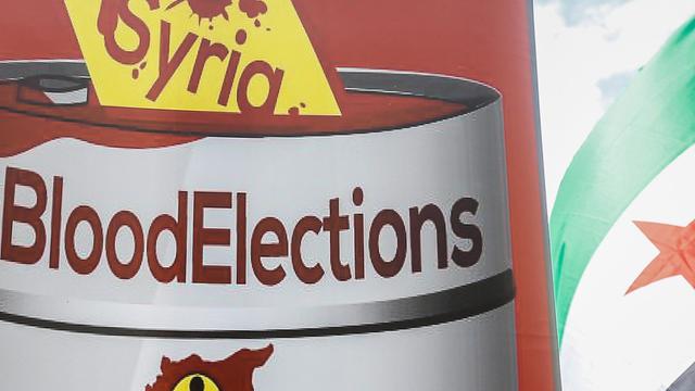 Ein Schild spricht von den "blutigen Wahlen" in Syrien.