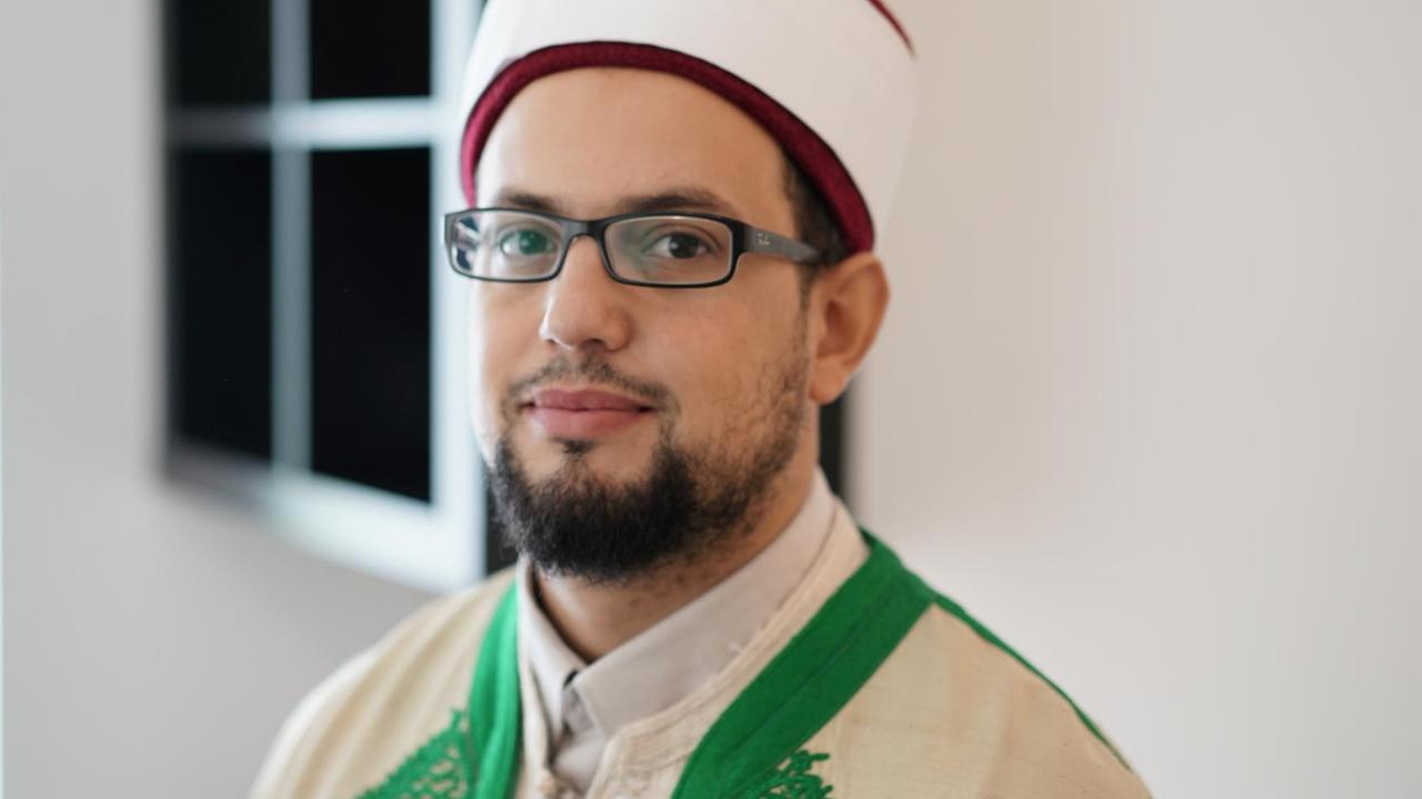 Porträt von Imam Mounib Doukali, mit weißer Kappe und in Amtsrobe.