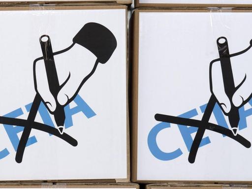 Kartons mit Formularen zur Verfassungsbeschwerde gegen das geplante Freihandelsabkommen zeigen eine Hand, die mit einem Stift den Schriftzug CETA durchstreicht