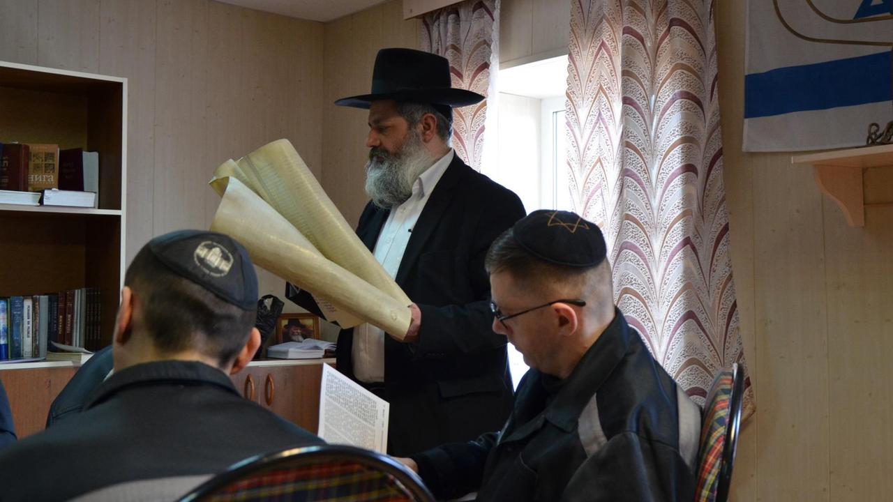 Rabbiner Ifrah Abramow steht am Tisch und hält Papierrollen Rabbiner Ifrah Abramow steht am Tisch und hält Papierrollen