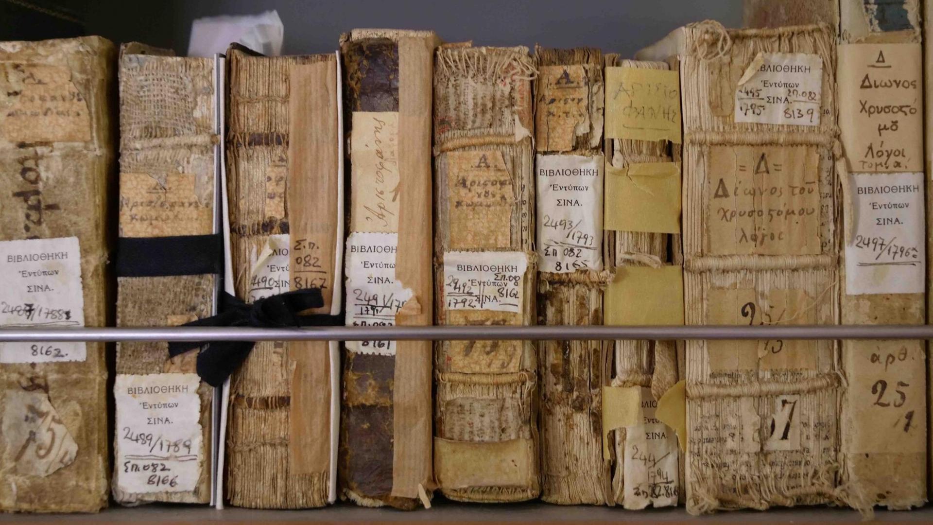 In einem Regal stehen sehr alte Bücher nebeneinander, die Buchrücken in Auflösung begriffen. In einem Regal stehen sehr alte Bücher nebeneinander, die Buchrücken in Auflösung begriffen.