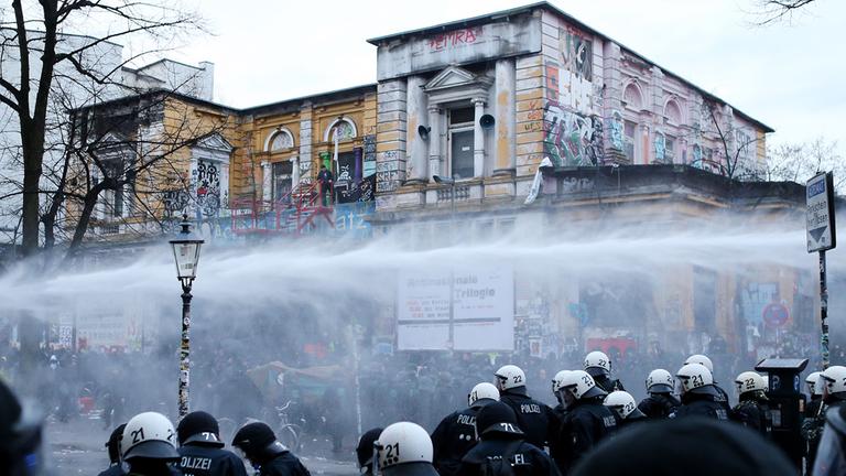 Demonstraten werden am 21.12.2013 vor dem Kulturzentrum "Rote Flora" im Schanzenviertel in Hamburg mit Wasserwerfern von der Polizei zurückgedrängt. Demonstraten werden am 21.12.2013 vor dem Kulturzentrum "Rote Flora" im Schanzenviertel in Hamburg mit Wasserwerfern von der Polizei zurückgedrängt.