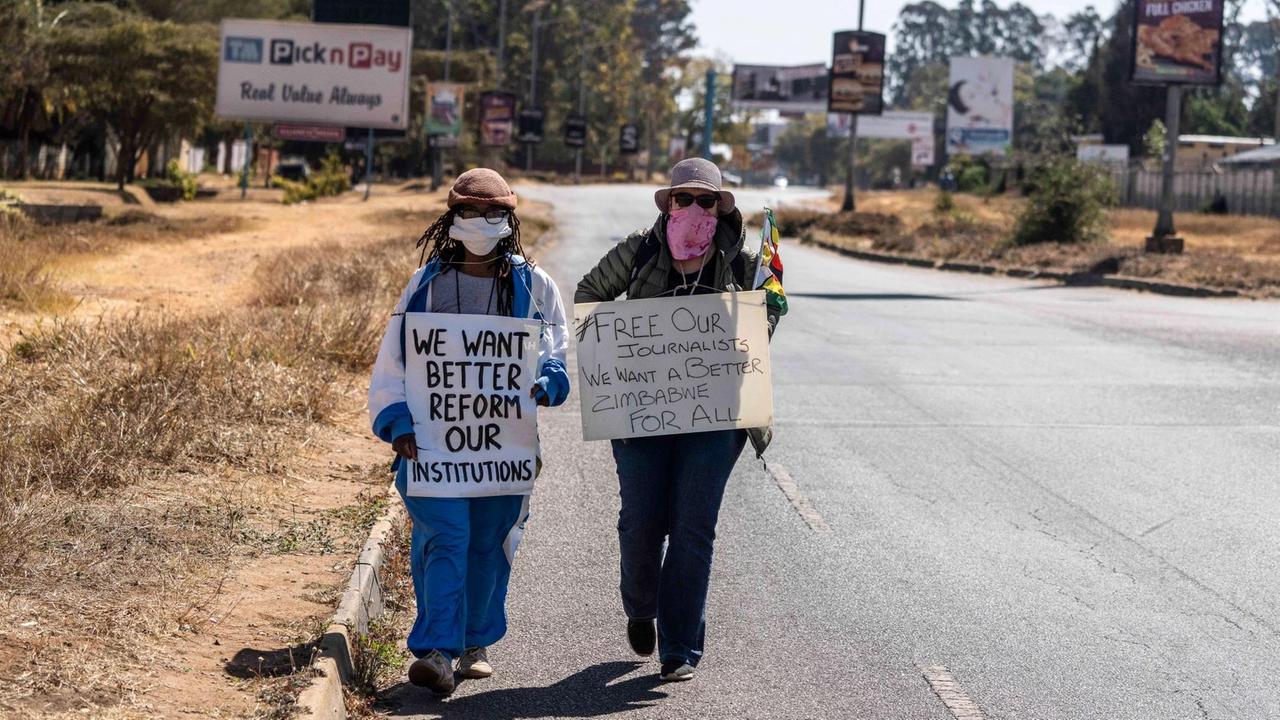 Anti-Korruptions-Protest in Simbabwe: zwei Frauen mit Maske halten Plakate.