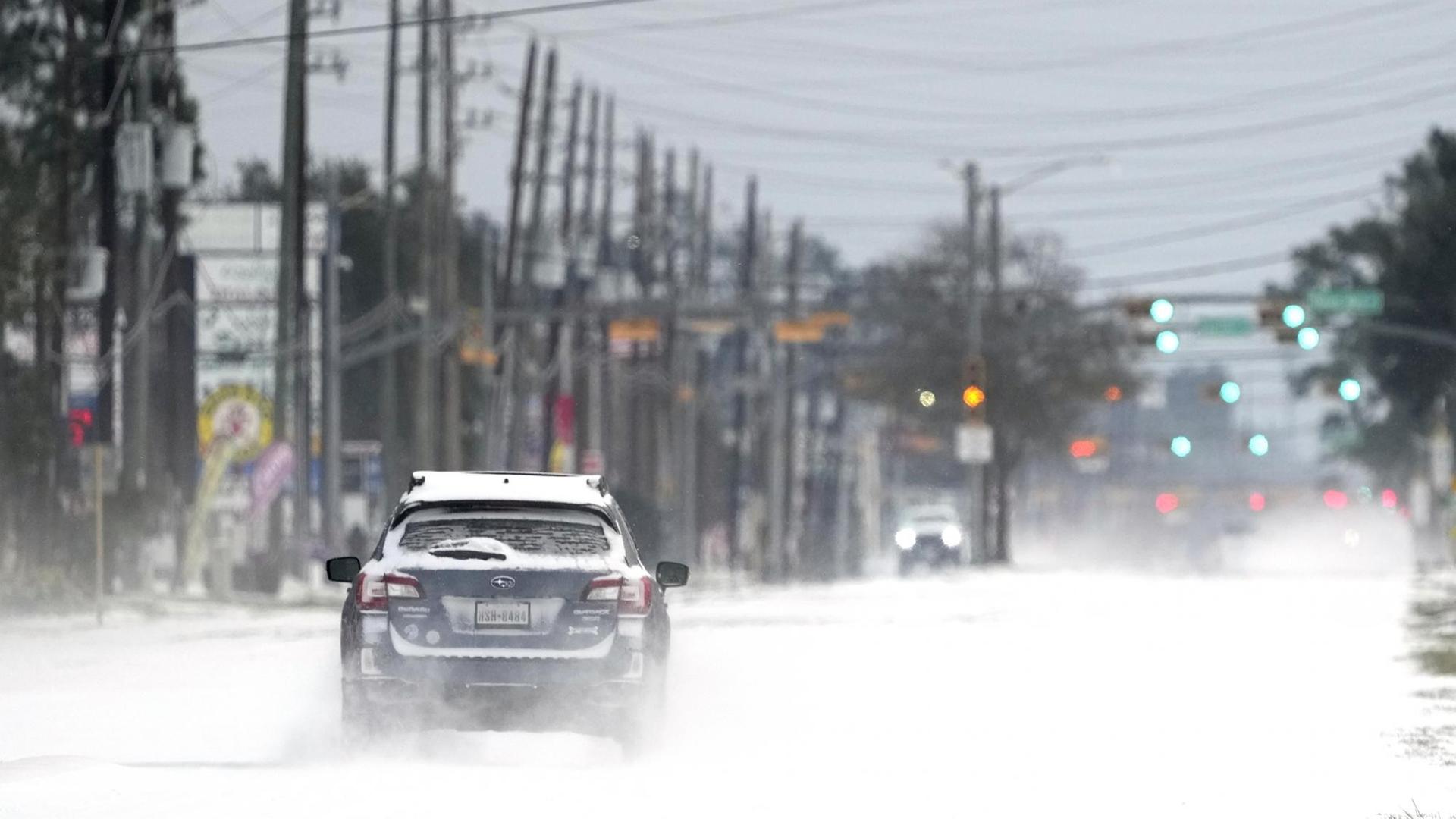 Ein Auto fährt in Texas auf einer zugeschneiten Straße.