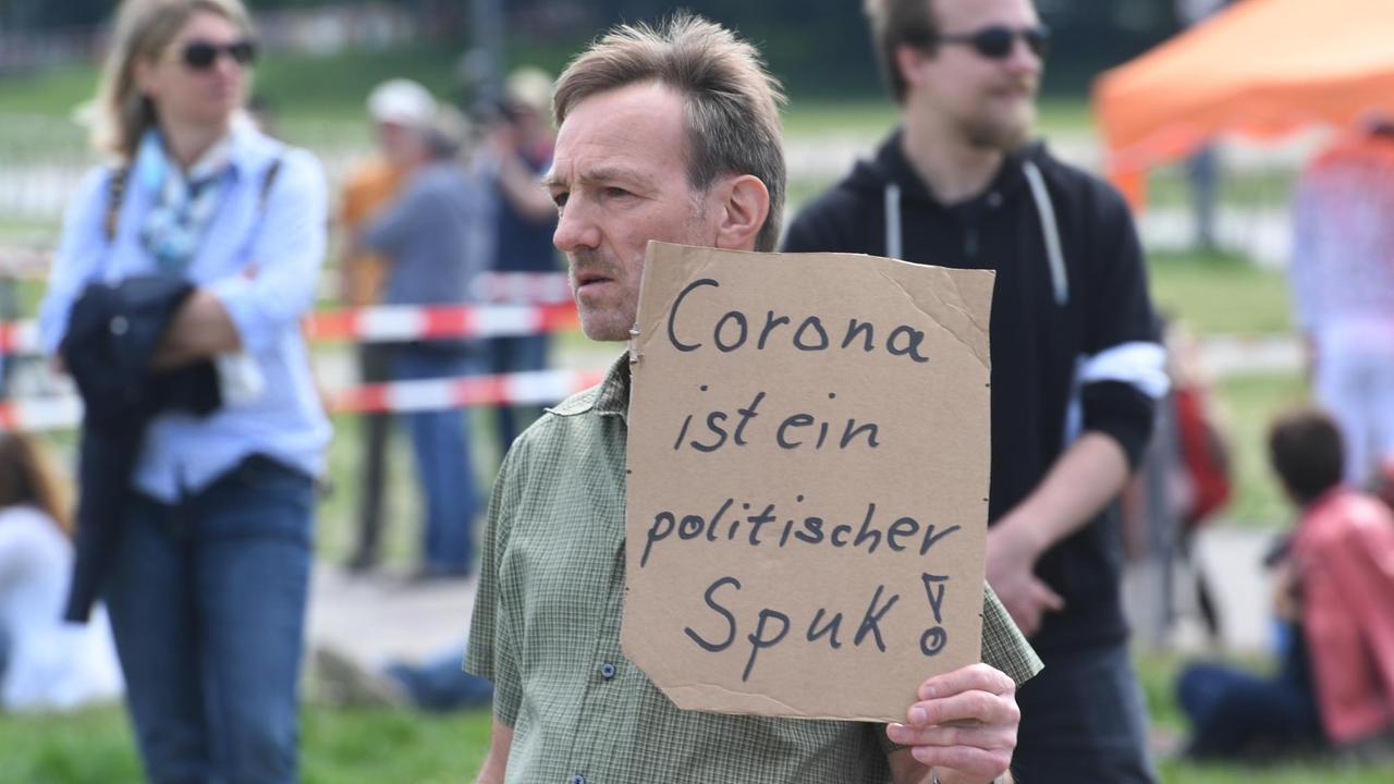 Ein Demonstrant auf der Münchner Theresienwiese. Er hält ein Schild mit der Aufschrift "Corona ist ein politischer Spuk!" Ein Demonstrant auf der Münchner Theresienwiese. Er hält ein Schild mit der Aufschrift "Corona ist ein politischer Spuk!"