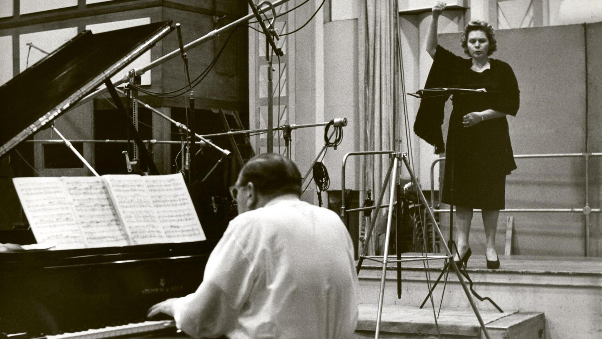 Links vorne ein Flügel, daran ein Pianist mit Rücken zum Betrachter. Rechts hinten eine Sängerin vor einem Mikrofon. Links vorne ein Flügel, daran ein Pianist mit Rücken zum Betrachter. Rechts hinten eine Sängerin vor einem Mikrofon.
