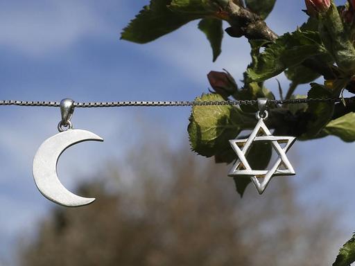 Ein Davidstern und eine Mondsichel hängen als Symbole für Judentum und Islam an einer Kette.