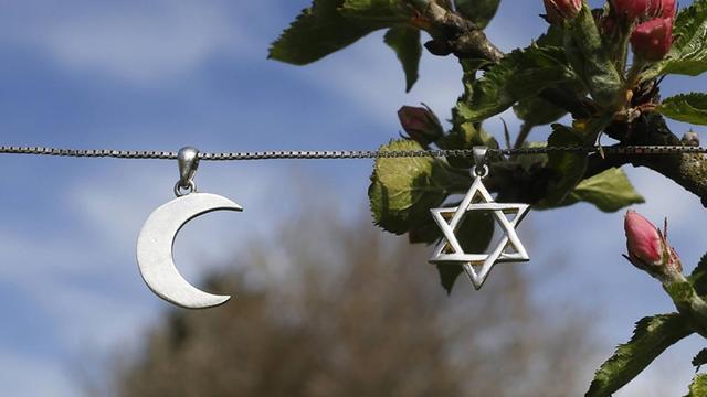 Ein Davidstern und eine Mondsichel hängen als Symbole für Judentum und Islam an einer Kette.