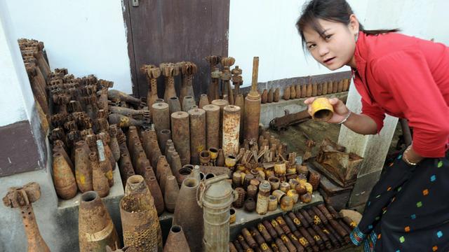 Eine Angestellte der Tourismusabteilung der Provinz Xiengkhoang zeigt unterschiedliche US-Bomben