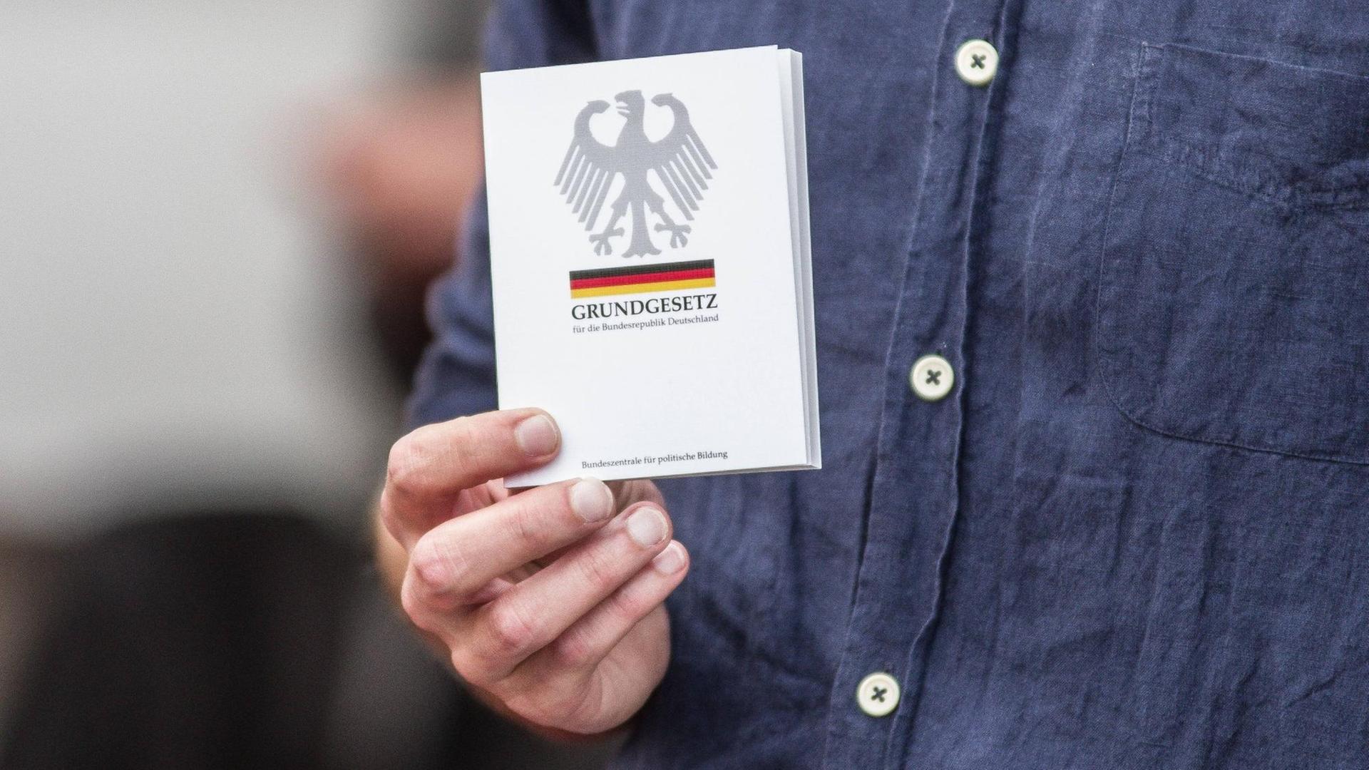Die Hand eines Mannes hälte eine Ausgabe des deutschen Grundgesetzes. Die Hand eines Mannes hälte eine Ausgabe des deutschen Grundgesetzes.