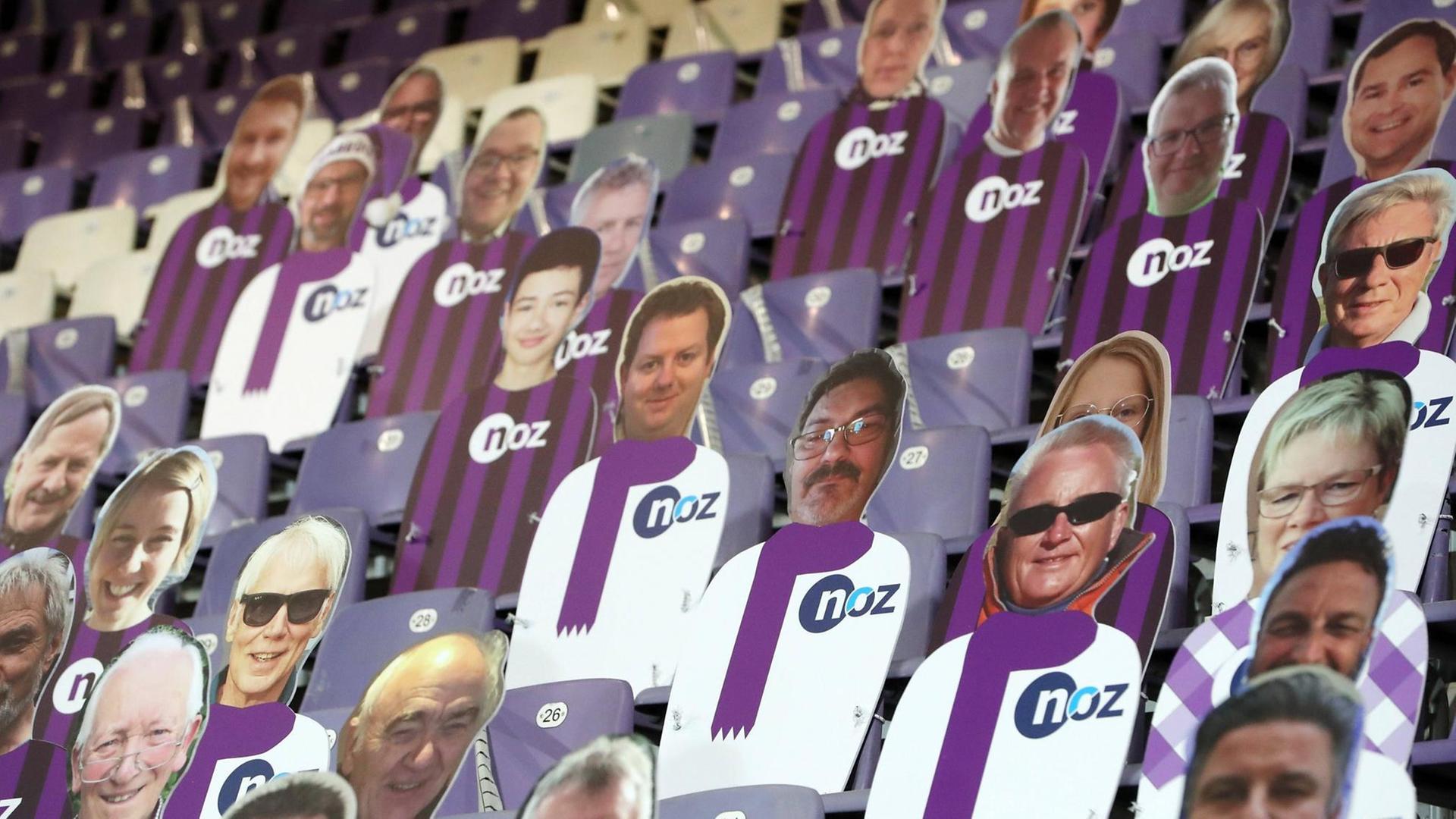 Auf der Tribüne in einem Fußballstadion sitzen statt echten Zuschauern Pappfiguren. Auf der Tribüne in einem Fußballstadion sitzen statt echten Zuschauern Pappfiguren.