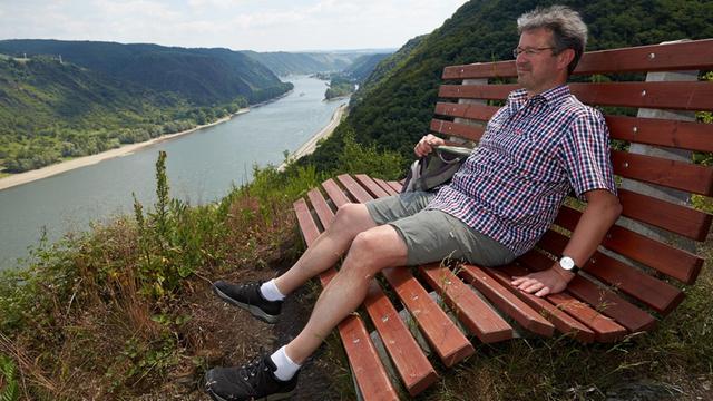 Der Moderator und Autor Manuel Andrack genießt am Wanderweg der Traumschleife Rheingold bei Hirzenach (Rheinland-Pfalz) die Aussicht auf das Rheintal.