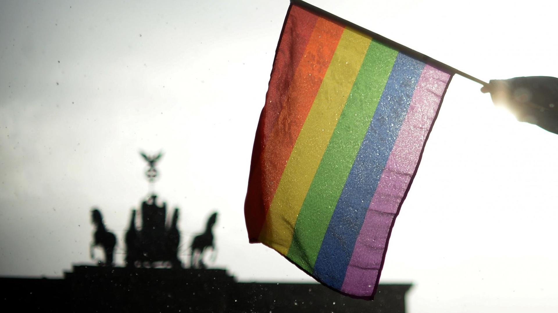 Eine Regenbogenflagge wird in Berlin beim Christopher Street Day (CSD) vor dem Brandenburger Tor gehalten. Eine Regenbogenflagge wird in Berlin beim Christopher Street Day (CSD) vor dem Brandenburger Tor gehalten.