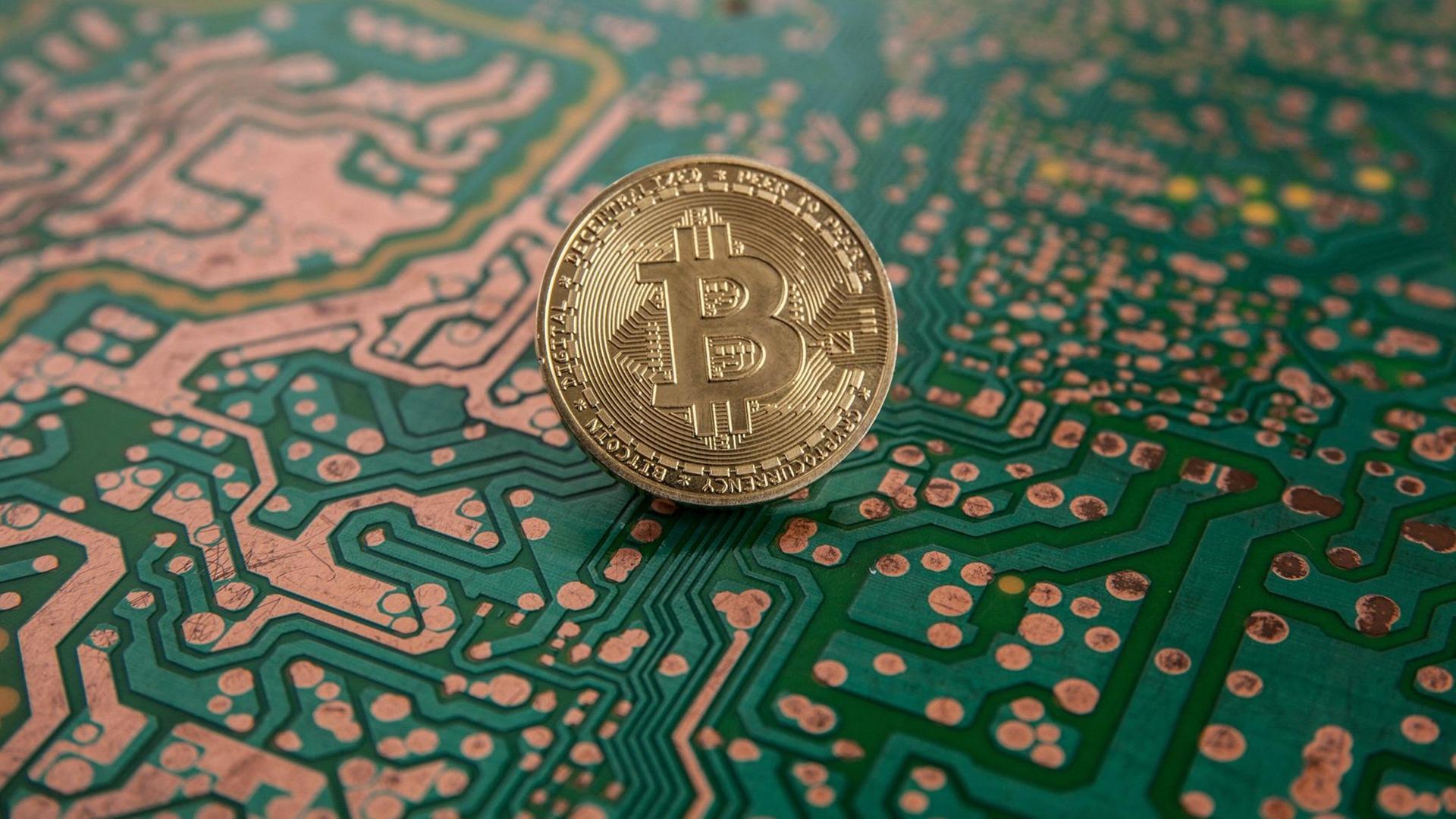 Auf dem Bild ist eine Münze mit einem "B" drauf zu sehen. Sie steht vor dem Hintergrund eines Computerchips.