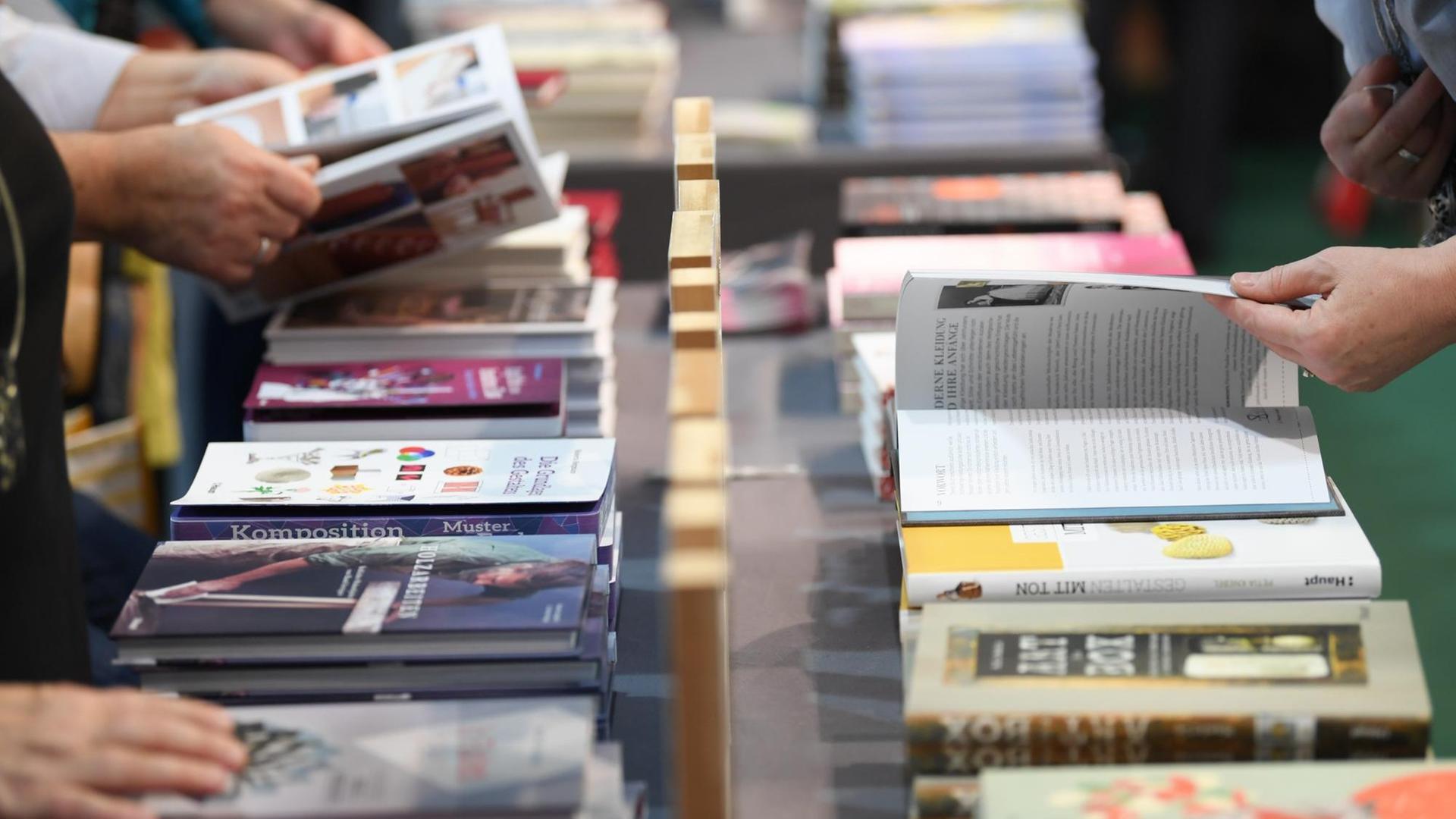 11.10.2018, Hessen, Frankfurt/Main: Besucher der Frankfurter Buchmesse blättern an einem Verlagsstand in Büchern. Die weltgrößte Bücherschau findet bis zum 14. Oktober statt.