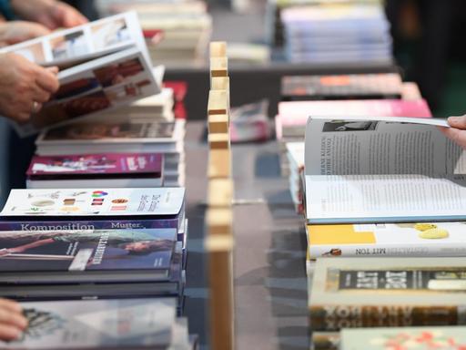 11.10.2018, Hessen, Frankfurt/Main: Besucher der Frankfurter Buchmesse blättern an einem Verlagsstand in Büchern. Die weltgrößte Bücherschau findet bis zum 14. Oktober statt.