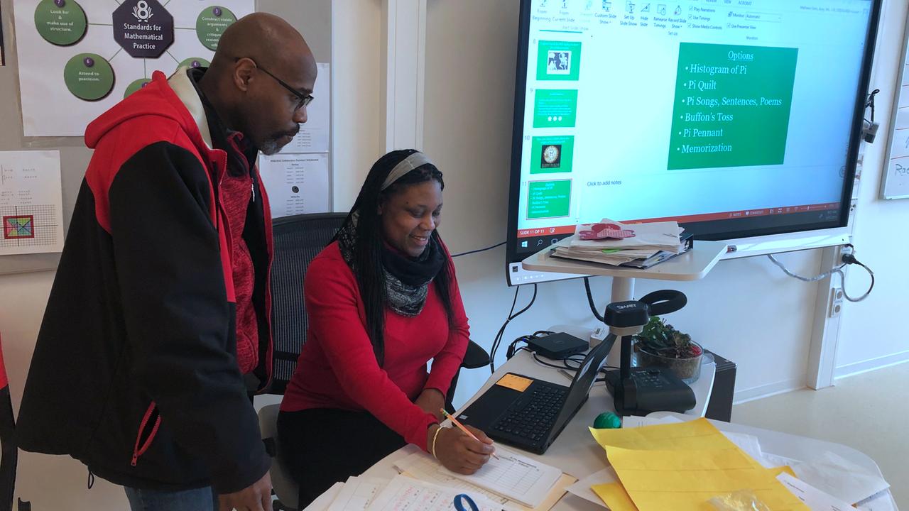 Barriet Smith schaut mit einer Kollegin auf einen Laptop, im Hintergrund ein Smartboard. Barriet Smith schaut mit einer Kollegin auf einen Laptop, im Hintergrund ein Smartboard.