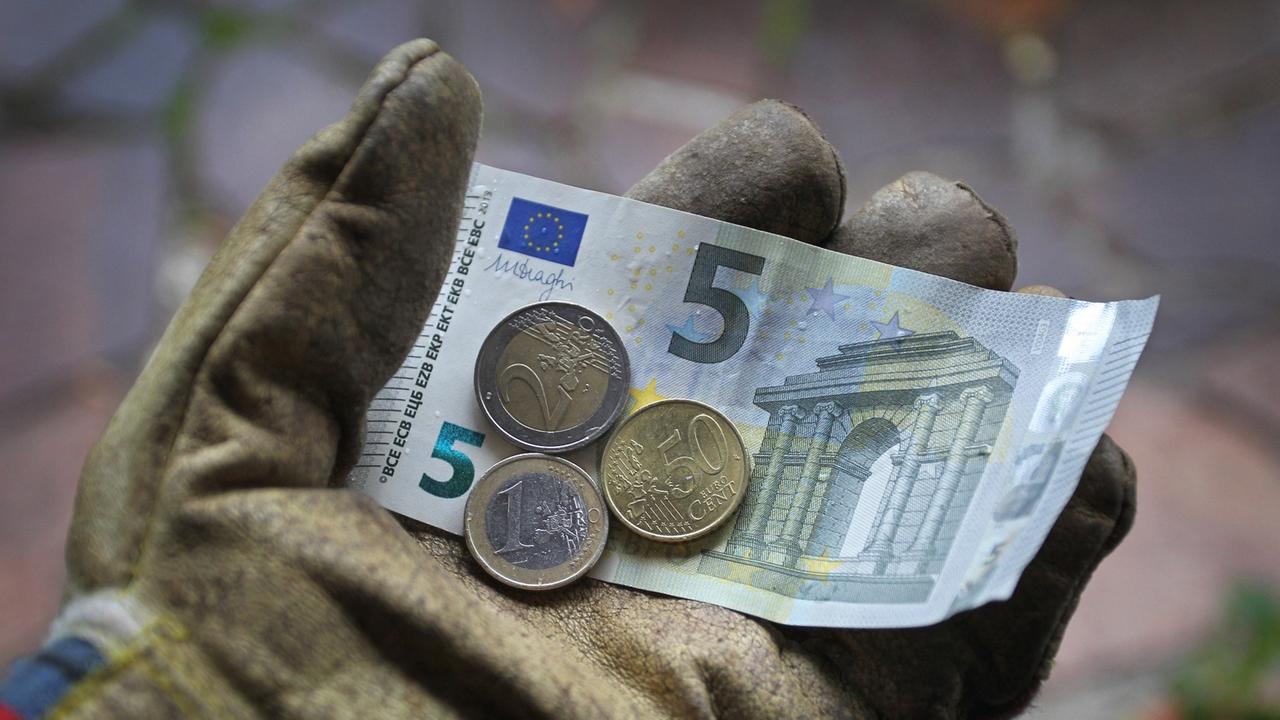 Ein Arbeitshandschuh in dem ein Fünf-Euro-Schein, eine Zwei-Euro-Münze, eine Ein-Euro-Münze sowie ein 50-Cent-Stück liegen.