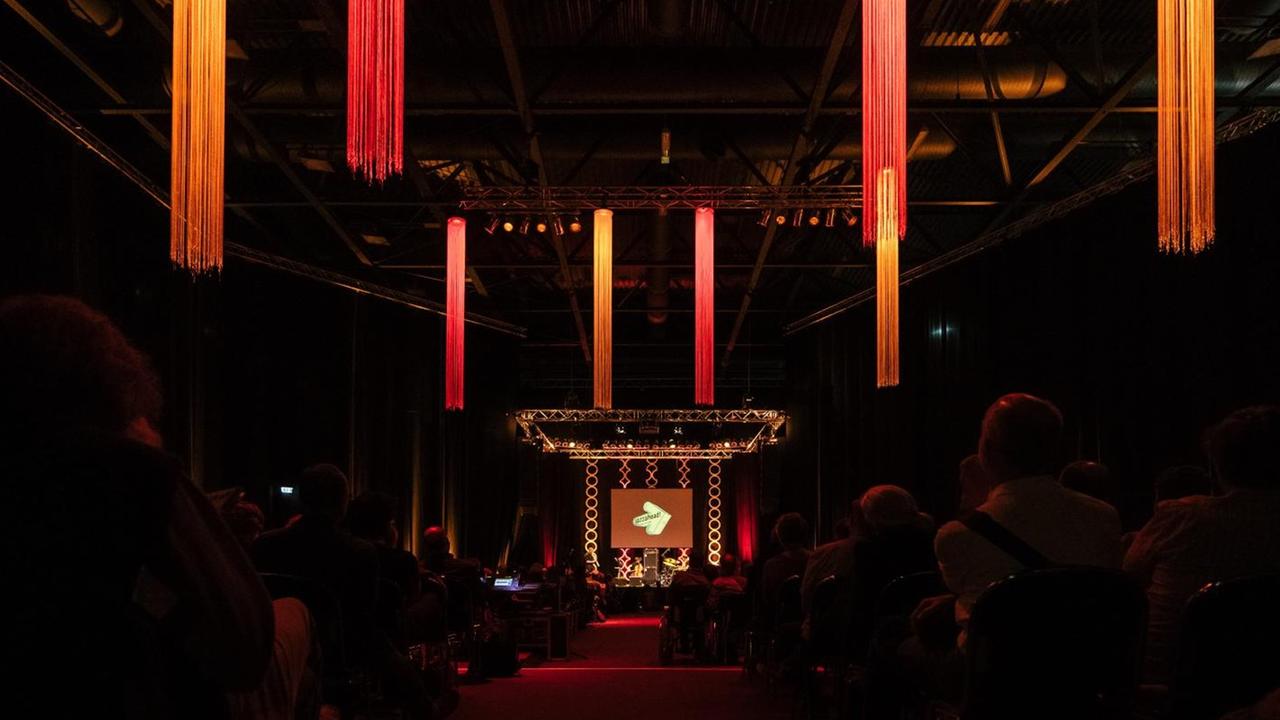 ein Saal mit Bühne und rot-orangener Ausleuchtung ein Saal mit Bühne und rot-orangener Ausleuchtung
