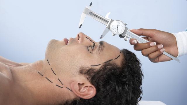 Die Nase eines Mannes vor einer Schönheitsoperation wird von einem Arzt vermessen