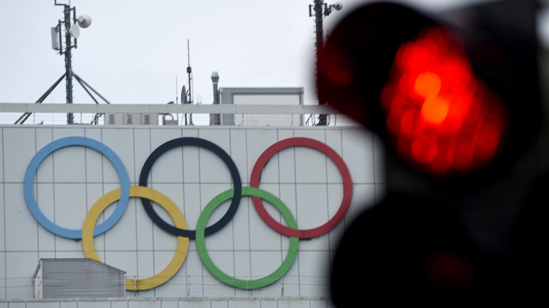 Das rote Licht einer Ampel neben den Olympischen Ringen Das rote Licht einer Ampel neben den Olympischen Ringen