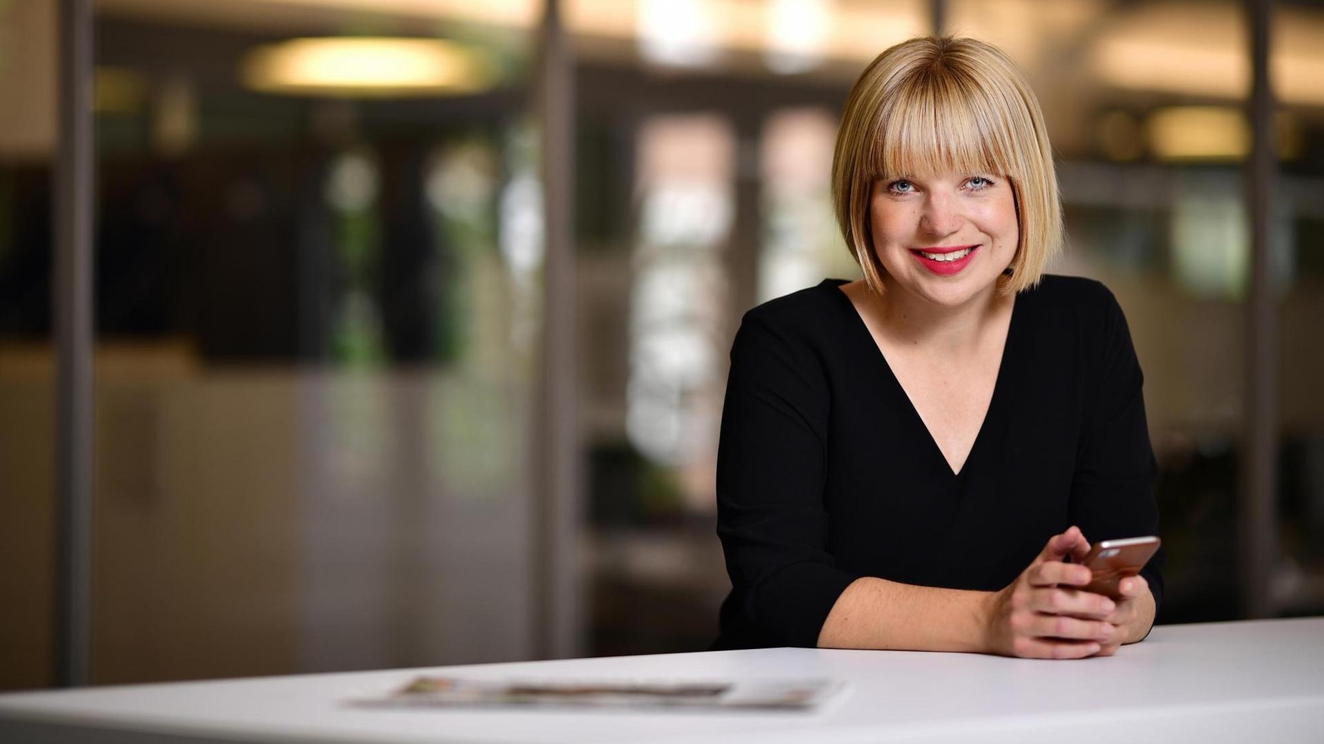 Die Chefredakteurin der Märkischen Allgemeinen Zeitung Hannah Suppa an einem Redaktionstisch mit einem Smartphone in der Hand, auf dem Tisch liegt eine Zeitung. Die Chefredakteurin der Märkischen Allgemeinen Zeitung Hannah Suppa an einem Redaktionstisch mit einem Smartphone in der Hand, auf dem Tisch liegt eine Zeitung.