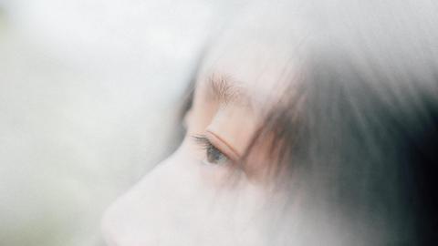 Leicht verschwommenes Bild einer Asiatin, welches hauptsächlich ihr Auge im Profil zeigt.