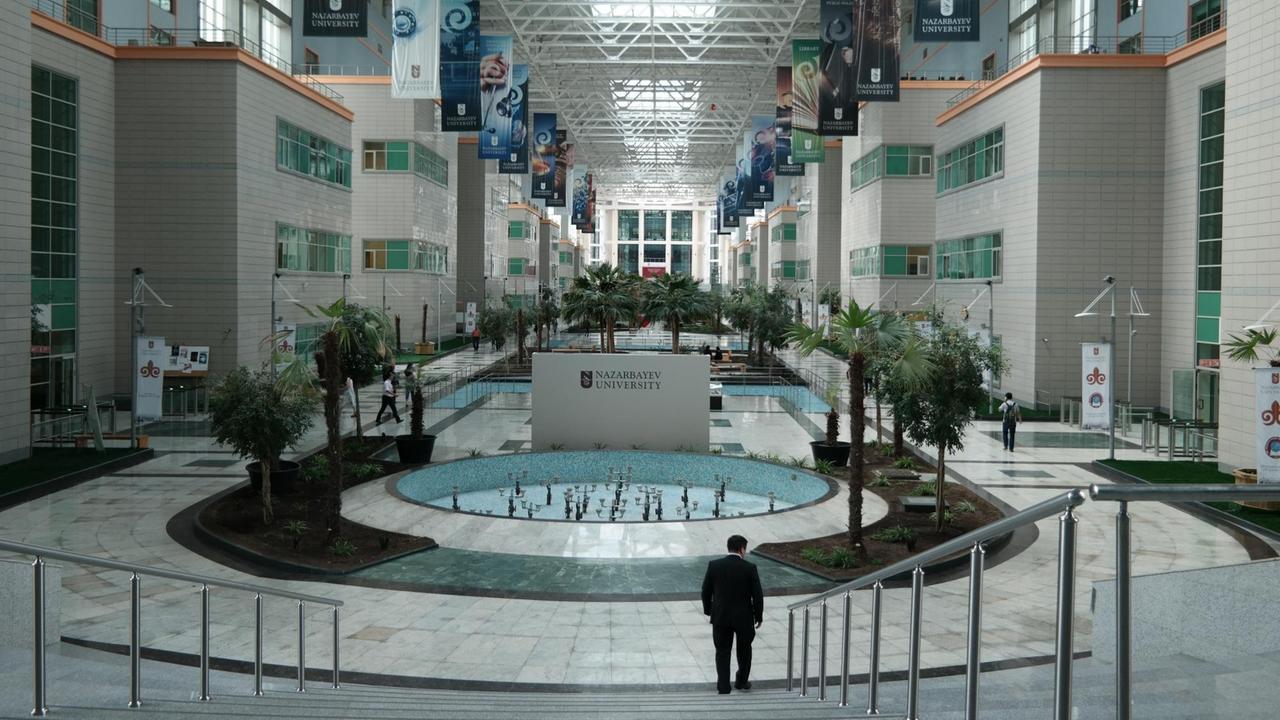 Das Hauptgebäude der Nasarbayev-Universität in Astana ist eine riesige Halle mit Wasserspielen und Fahnen.