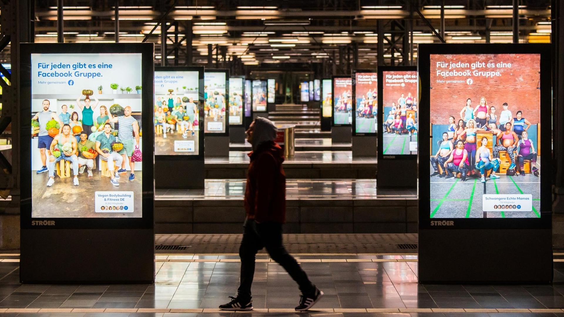 Ein Mann geht über einen leeren Bahnsteig, im Hintergrund Werbung von Facebook. Ein Mann geht über einen leeren Bahnsteig, im Hintergrund Werbung von Facebook.