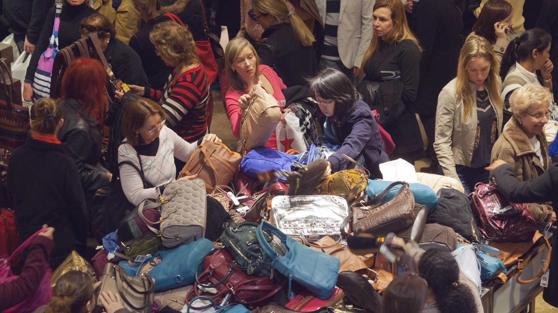 Einige Damen wühlen in einem bunten Handtaschenberg bei Macy´s in New York.