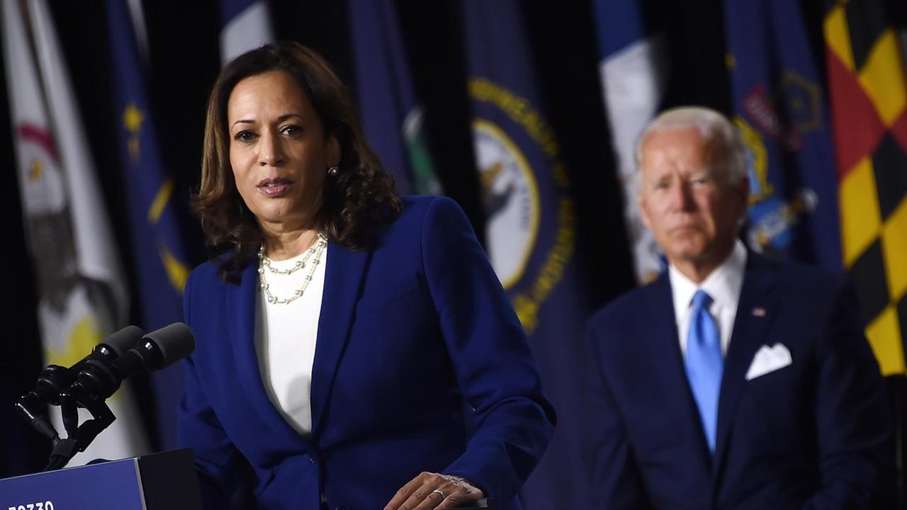 Kamala Harris und Joe Biden treten mit Corona-bedingten Abstand zueinander gemeinsam auf einer Bühne auf. Harris steht am Redepult während Biden ihr zuhört. Kamala Harris und Joe Biden treten mit Corona-bedingten Abstand zueinander gemeinsam auf einer Bühne auf. Harris steht am Redepult während Biden ihr zuhört.