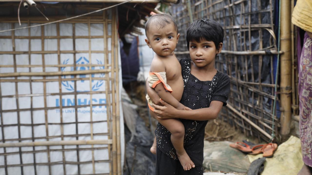Ein Flüchtlingsmädchen der Rohingya hält ein Kleinkind auf dem Arm. Das Bild stammt aus dem Kutupalong-Flüchtlingslager im Bezirk Cox's Basar in Bangladesch im Juni 2018. Ein Flüchtlingsmädchen der Rohingya hält ein Kleinkind auf dem Arm. Das Bild stammt aus dem Kutupalong-Flüchtlingslager im Bezirk Cox's Basar in Bangladesch im Juni 2018.