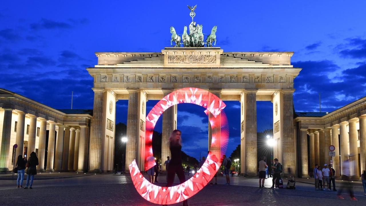Eine Lichtkünstlerin performt mit roten Lichtern vor dem Brandenburger Tor. Mit leuchtenden Mahnmalen hat die Veranstaltungsbranche am Abend auf ihre Lage in der Corona-Krise hingewiesen. Eine Lichtkünstlerin performt mit roten Lichtern vor dem Brandenburger Tor. Mit leuchtenden Mahnmalen hat die Veranstaltungsbranche am Abend auf ihre Lage in der Corona-Krise hingewiesen.