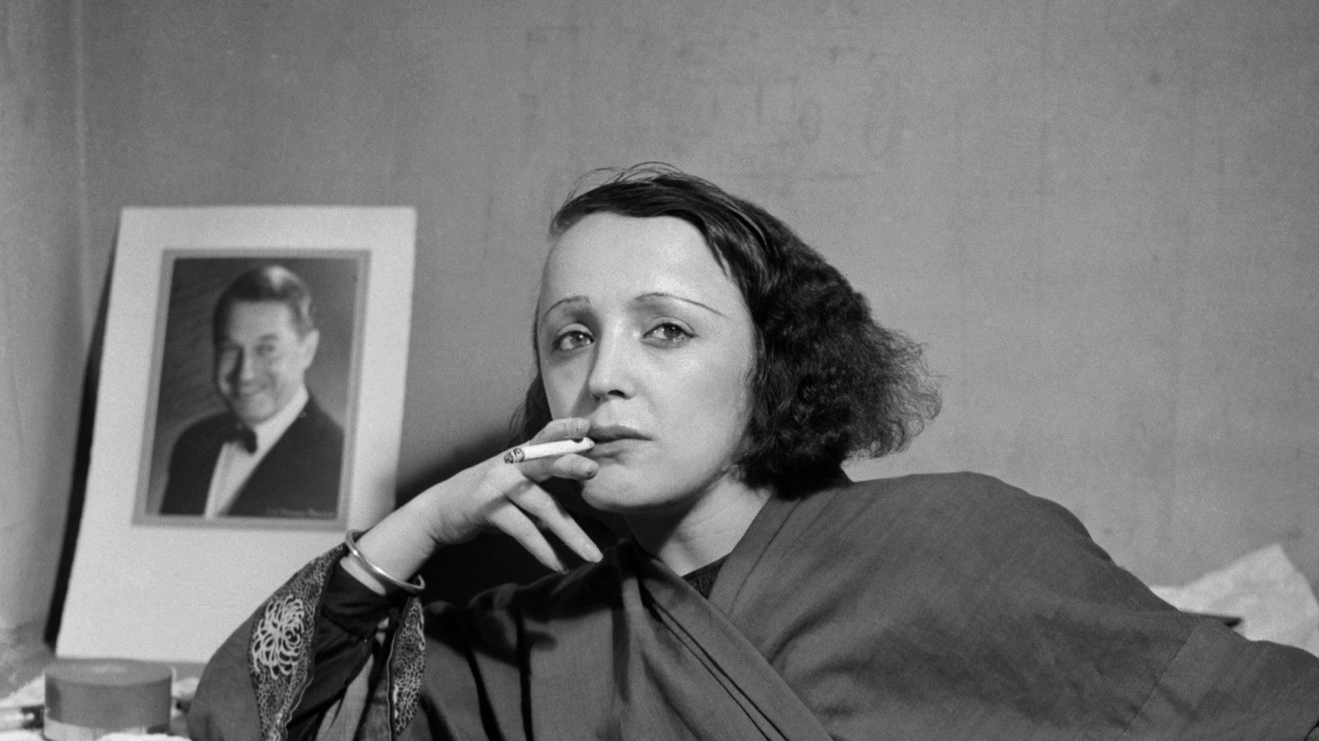 Die Sängerin Edith Piaf vor einem Bild von Maurice Chevalier im Jahr 1947.