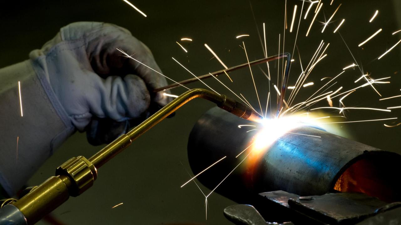 Ein Schweißer verbindet zwei Metallteile. Ein Schweißer verbindet zwei Metallteile.