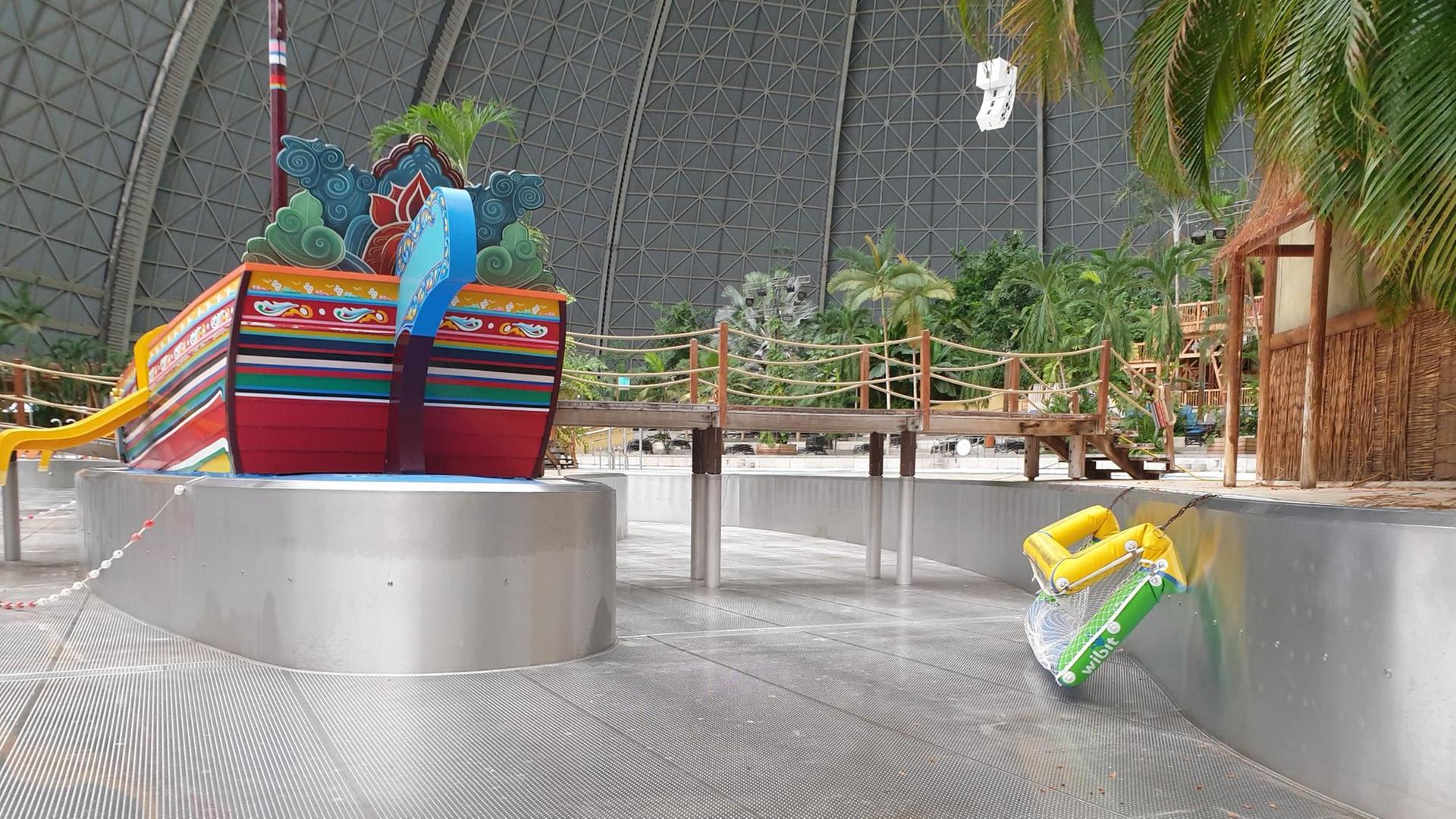 Ein Wasserbecken ohne Wasser in der Ferienanlage Tropical Island in Brandenburg. In der Mitte eine angelegte Insel aus Metall mit dekorativem Schiff, ein Steg führt vom Ufer dorthin, rechts liegt eine aufgeblasene Matratze an der Beckenwand. Ein Wasserbecken ohne Wasser in der Ferienanlage Tropical Island in Brandenburg. In der Mitte eine angelegte Insel aus Metall mit dekorativem Schiff, ein Steg führt vom Ufer dorthin, rechts liegt eine aufgeblasene Matratze an der Beckenwand.