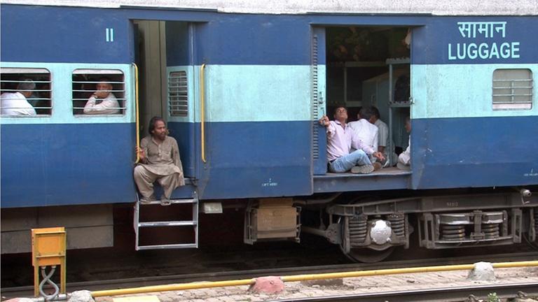 Zugreisende in Indien - 2 Fahrgäste sitzen an der offenen Tür - es sieht gefährlich aus.