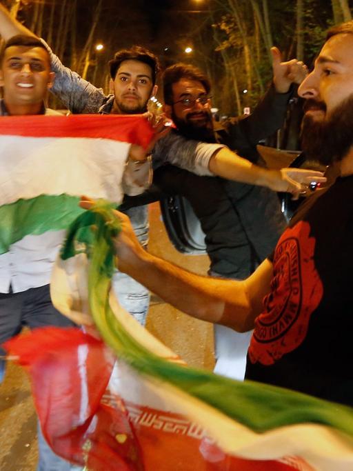 In einer Straße der iranischen Hauptstadt Teheran halten junge Iraner die Nationalflagge in die Luft, während sie die Übereinkunft im Atomstreit feiern.